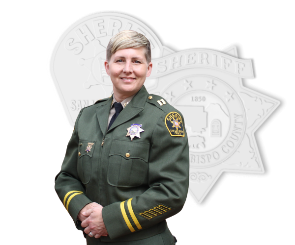 Correctional Captain standing in front of stylized badge and patch.